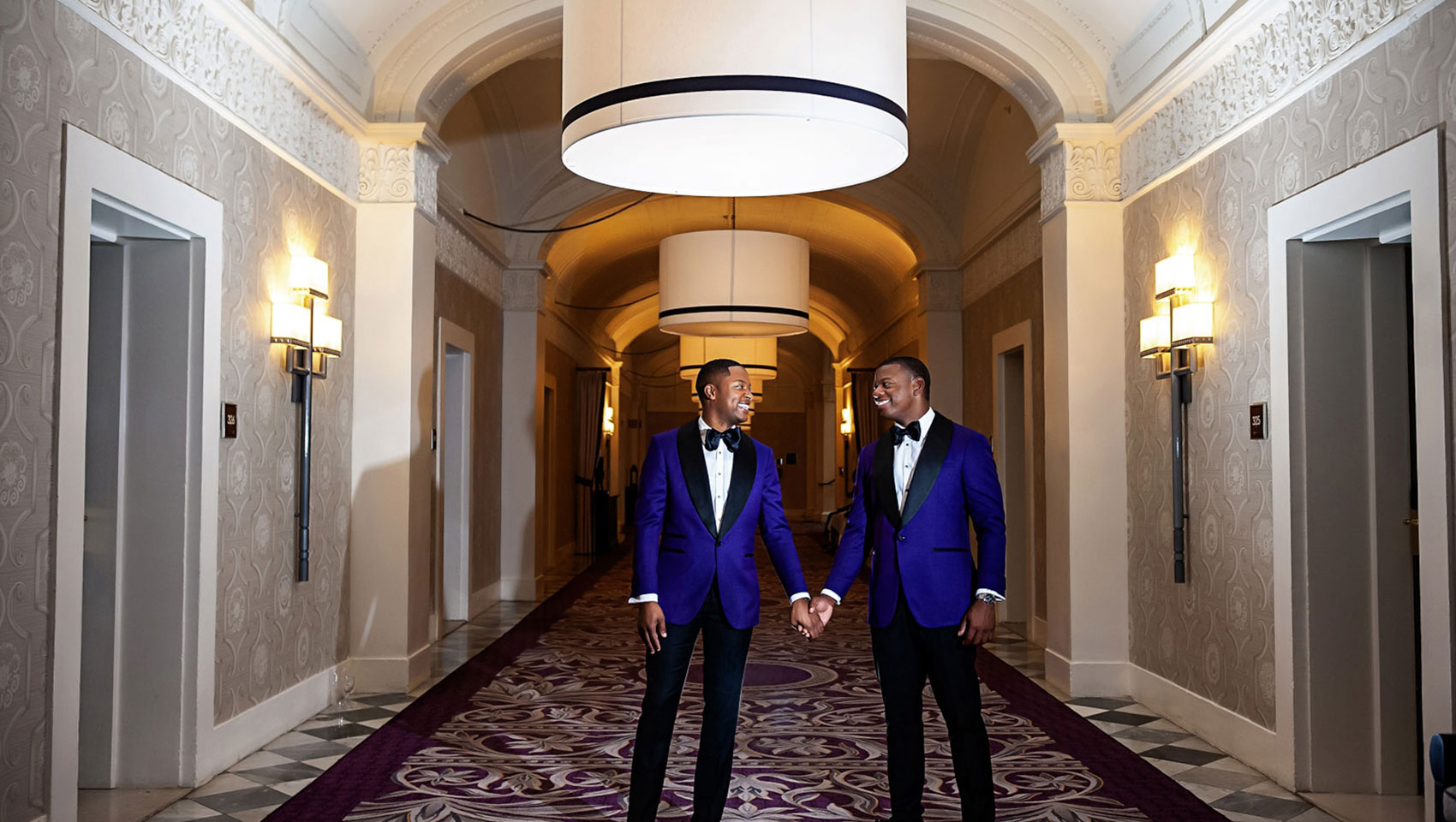 Grooms hold hands in the hallways at Kimpton Hotel Monaco Washington DC