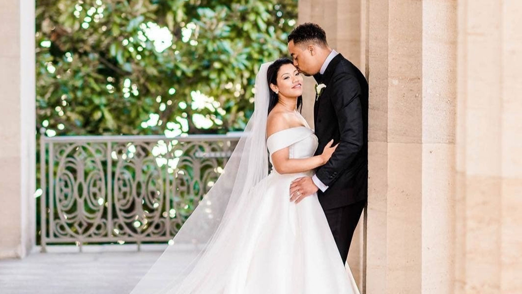 groom kiss brides cheek as he leans on columns during outdoor photoshoot at Kimpton Hotel Monaco Washington DC
